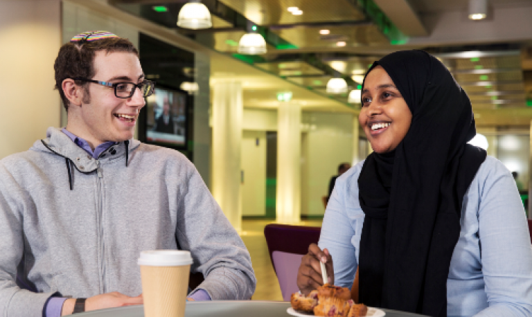 two young people smiling and talking over coffee