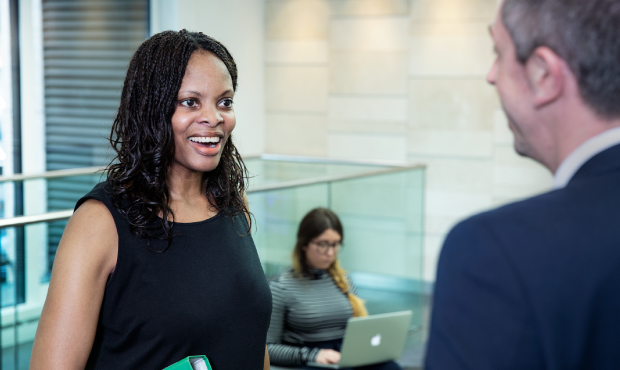 A woman holding a folder at work, in conversation